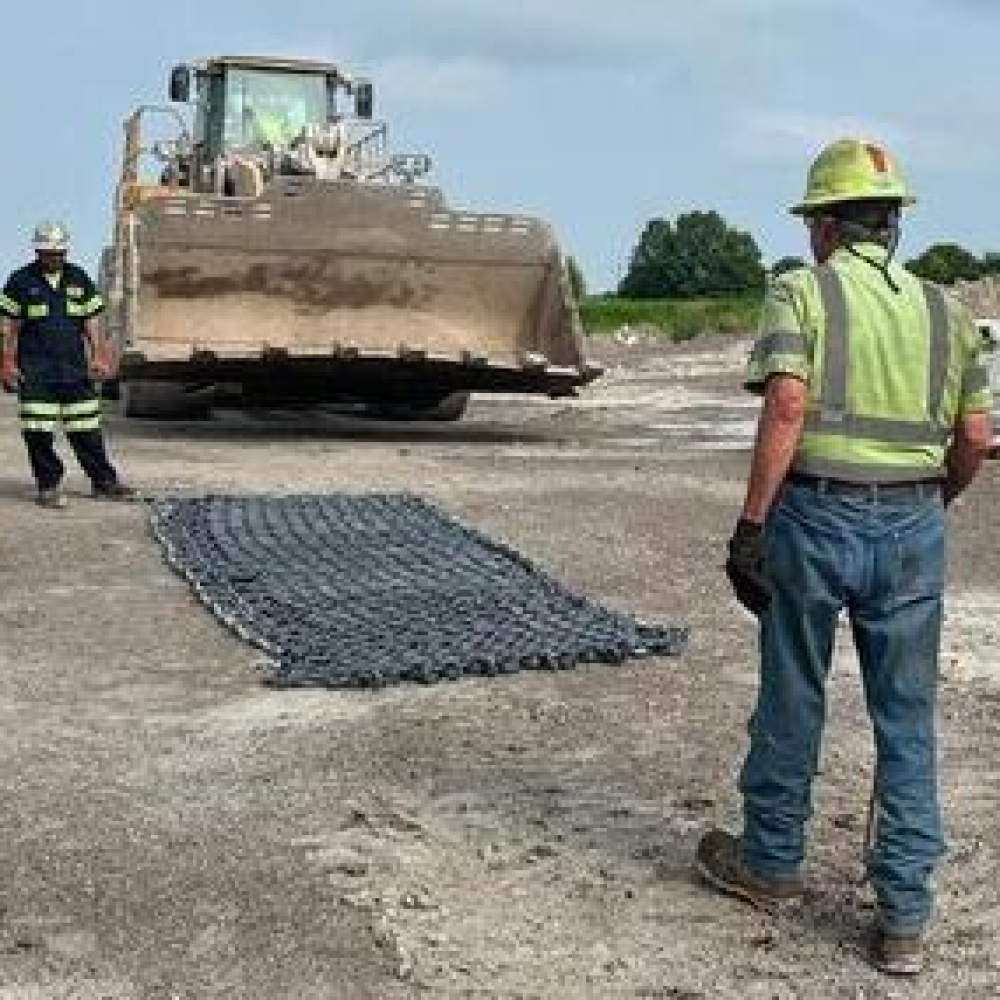 Workers preparing to install a traction chain on a construction site.