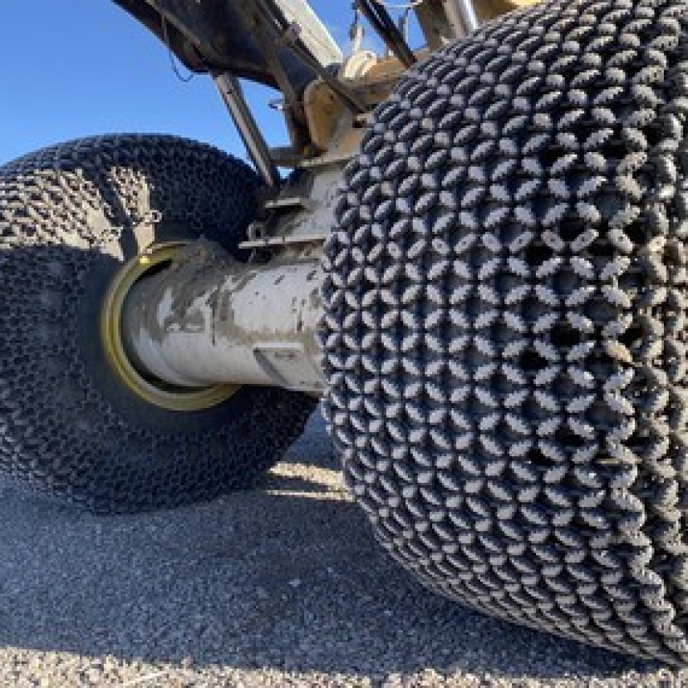 Close-up of heavy machinery tires equipped with traction chains for improved performance.