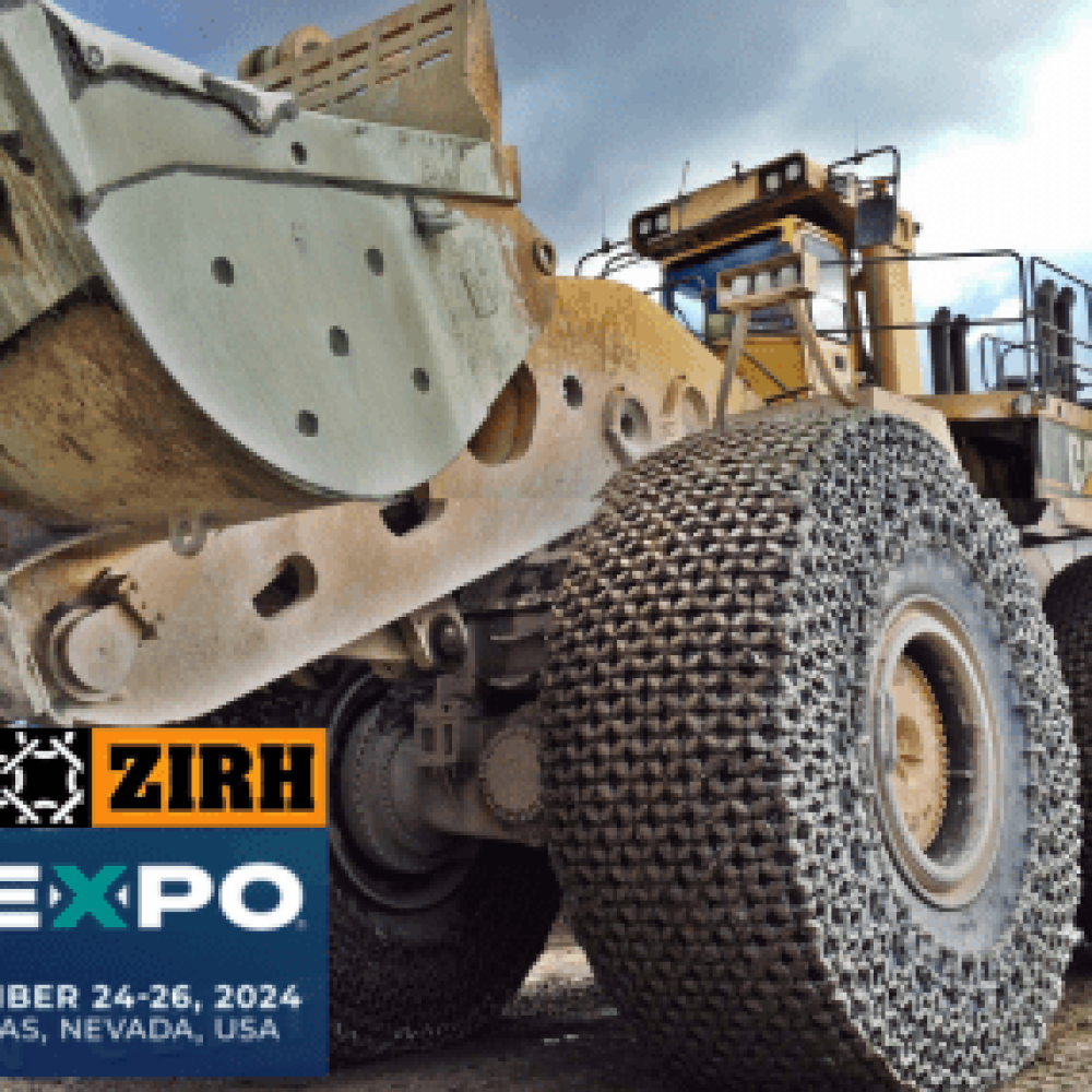 Large articulated vehicle with traction chains in a mining environment.