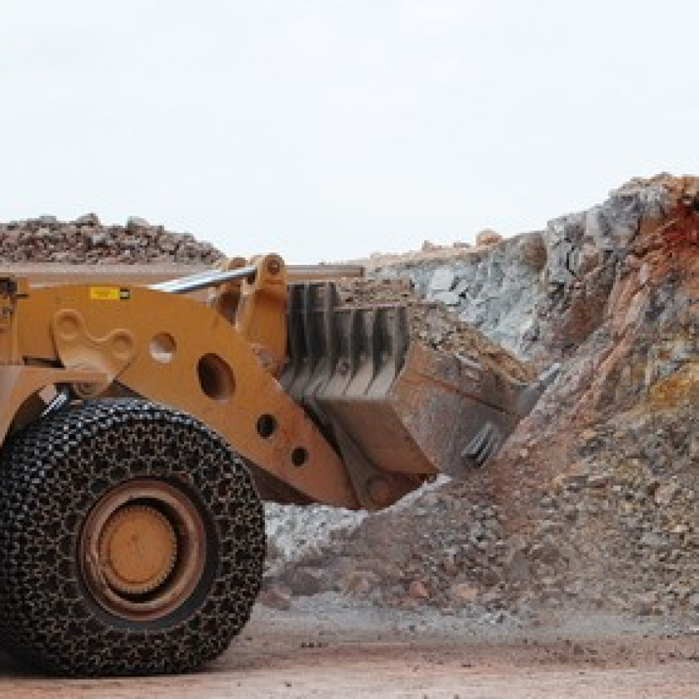 Large wheel loader equipped with traction chains on a construction site.