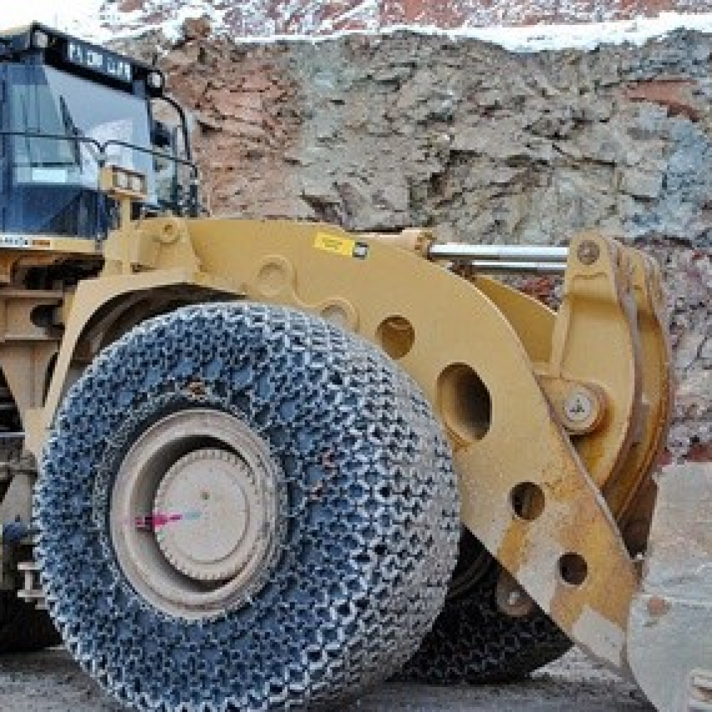 Heavy machinery equipped with traction chains in a rugged quarry environment.