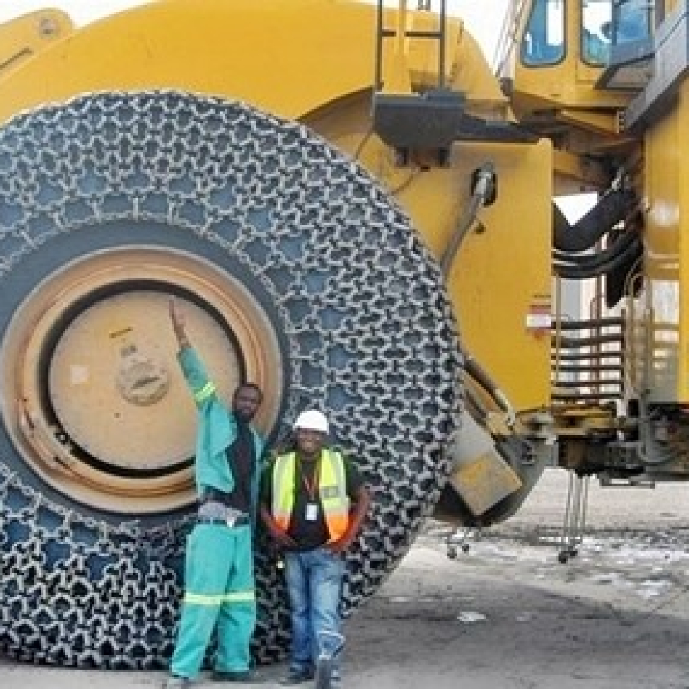 Tire protection chain on heavy machinery wheel at a construction site.