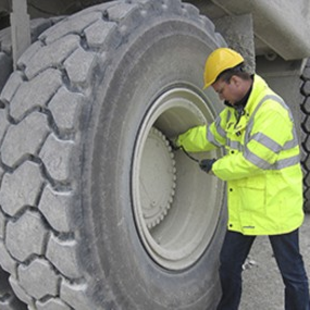Worker checking the tire of heavy machinery at a construction site.