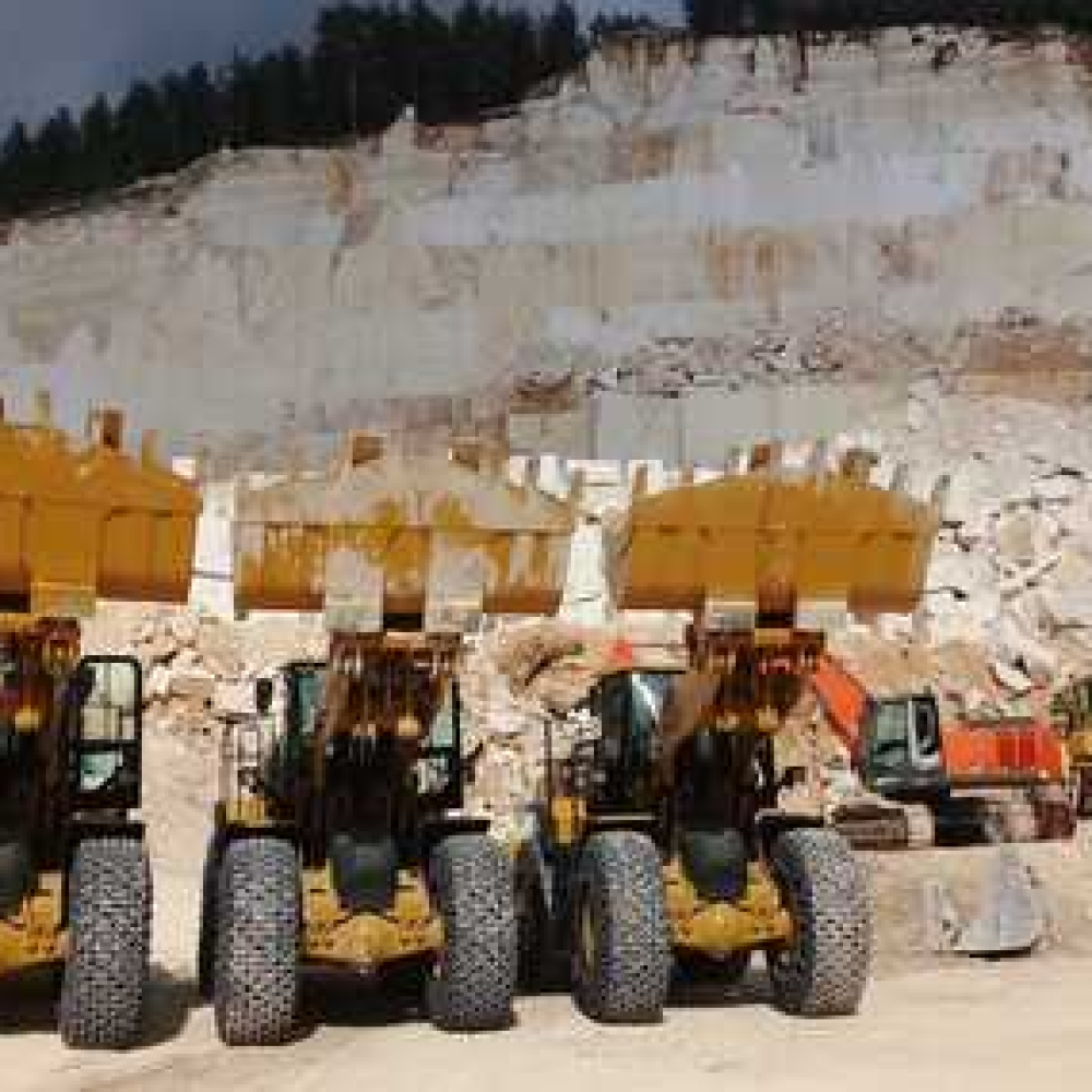 Heavy machinery operating at a quarry site with loaders and excavators visible.